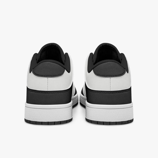 Rear view of black and white sneakers showing dark charcoal heel overlays, white leather collars, and black interior collar lining above white midsoles.