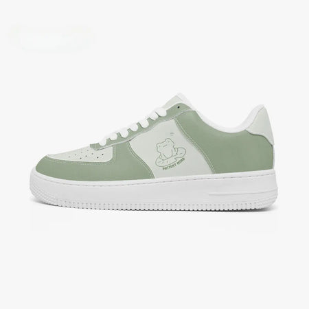 Side profile view of the left sneaker in sage green and light mint leather, highlighting the "PATIENT MIND" frog illustration, sage green panels, white laces, and white cupsole facing right.