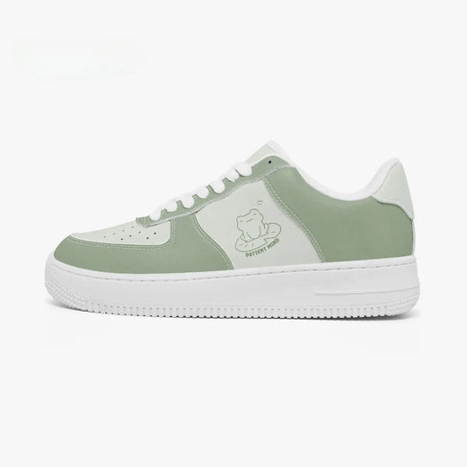 Side profile view of the left sneaker in sage green and light mint leather, highlighting the "PATIENT MIND" frog illustration, sage green panels, white laces, and white cupsole facing right.