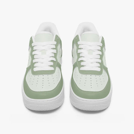 Front-facing top angle of low-top sneakers in sage green and light mint leather, displaying clean white laces, sage green eyestays, and perforated mint green toe boxes.