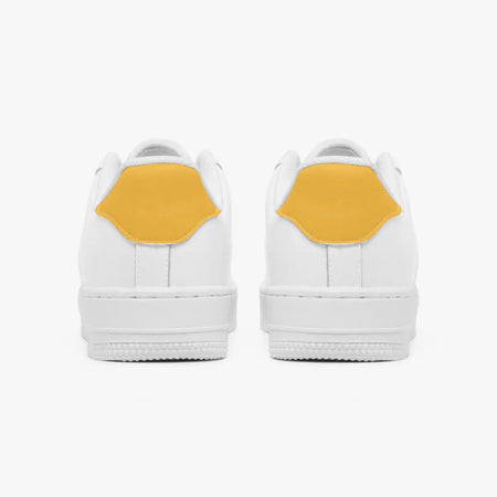 Rear view of white sneakers displaying mustard yellow heel tabs above thick white rubber outsoles.