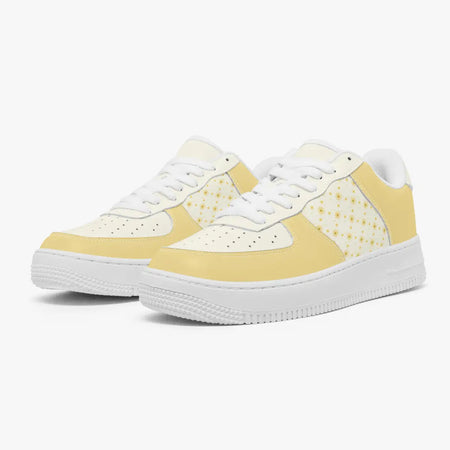 Angled three-quarter view of soft yellow and off-white sneakers featuring a delicate allover daisy pattern on the side panels.