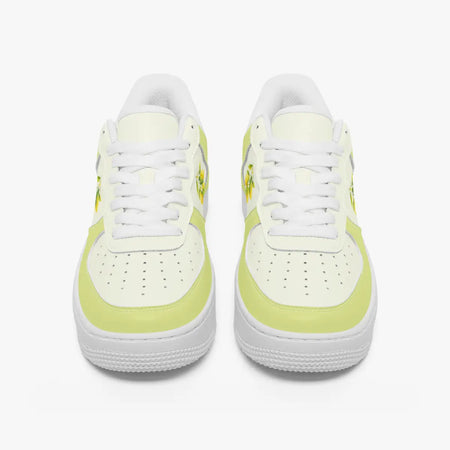 Front view of a pair of pastel yellow and off-white low-top sneakers with white laces and perforated toe caps on a plain background.