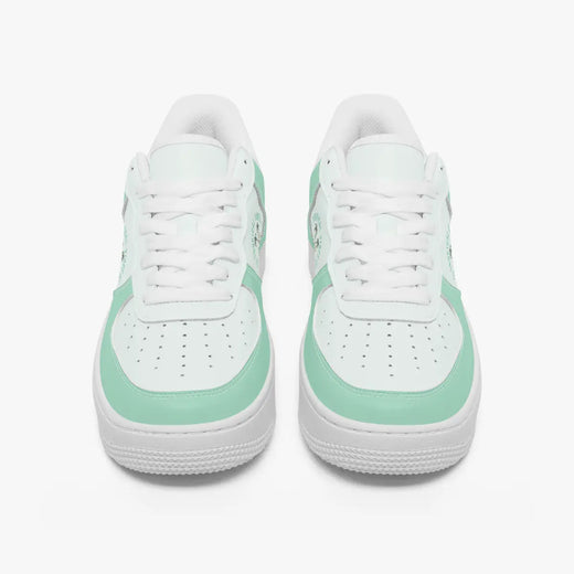 Front view of a pair of mint green and white low-top sneakers with white laces and perforated toe caps on a plain background.