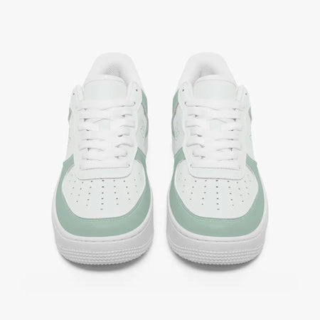 A pair of white low-top sneakers with mint green side panels and matching green trim around the midsole, shown from a front-facing perspective on a light gray background.