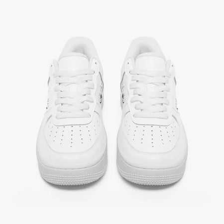 Front view of a pair of minimalist all-white low-top leather sneakers with matching white laces and perforated toe caps on a plain background.
