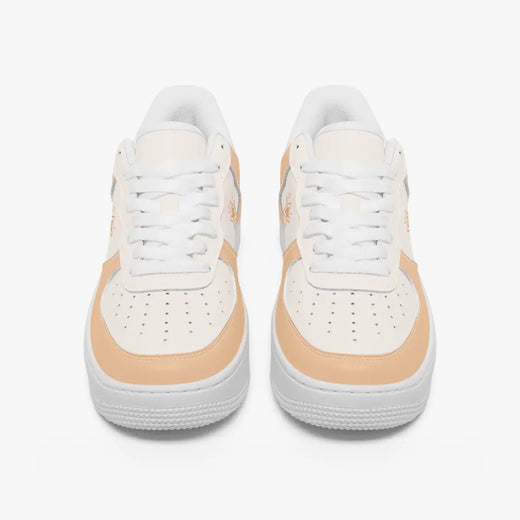 A pair of low-top sneakers shown from the front on a light gray background. The shoes are primarily white with a warm peach-beige accent panel around the midfoot and toe area.