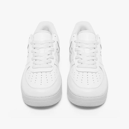 Front view of a pair of minimalist all-white low-top leather sneakers with white laces and perforated toe caps on a clean white background.