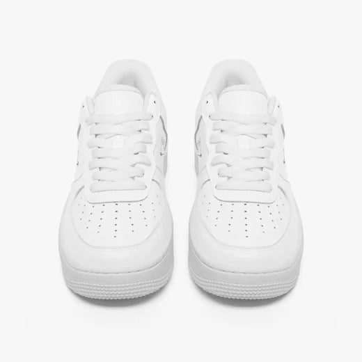 Front view of a pair of minimalist all-white low-top leather sneakers with white laces and perforated toe caps on a clean white background.