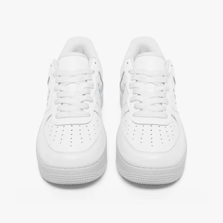 Front view of a pair of minimalist all-white low-top leather sneakers with white laces and perforated toe caps on a clean white background.
