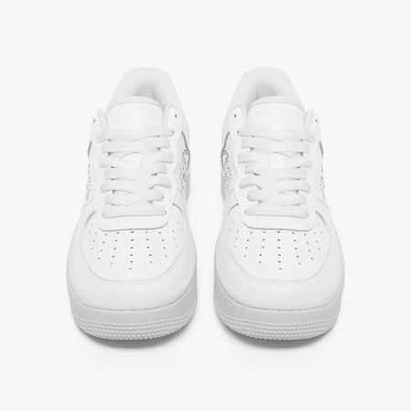 Front view of a pair of minimalist all-white low-top leather sneakers with white laces and perforated toe caps on an isolated white background.