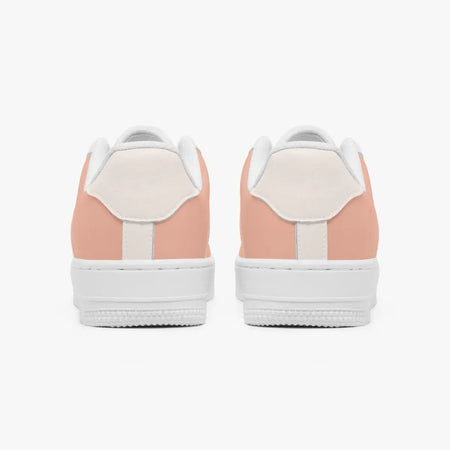 Rear view of a pair of dusty rose and cream low-top sneakers showing the padded heel counters and flat white rubber soles.
