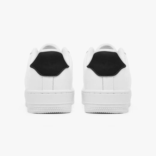 Rear view of white low-top sneakers showing solid black heel tabs and flat white rubber outsoles.