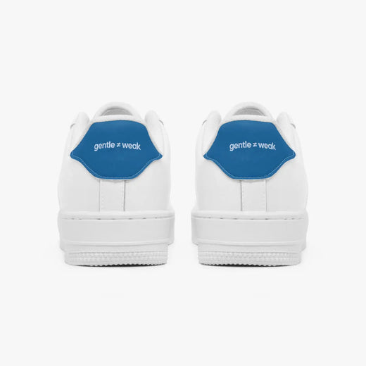 A pair of white low-top sneakers shown from the back, featuring a prominent blue heel tab with the white text 'gentle = weak'.