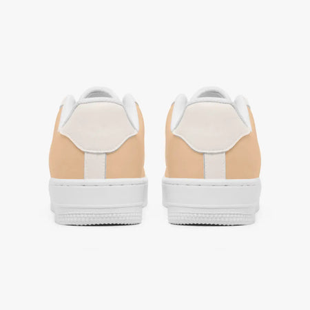 A pair of low-top sneakers shown from the back, featuring a light peach-beige suede upper with white leather heel tabs and thick white rubber soles, set against a plain white background.