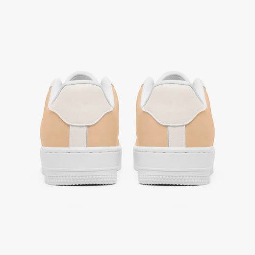 A pair of low-top sneakers shown from the back, featuring a light peach-beige suede upper with white leather heel tabs and thick white rubber soles, set against a plain white background.
