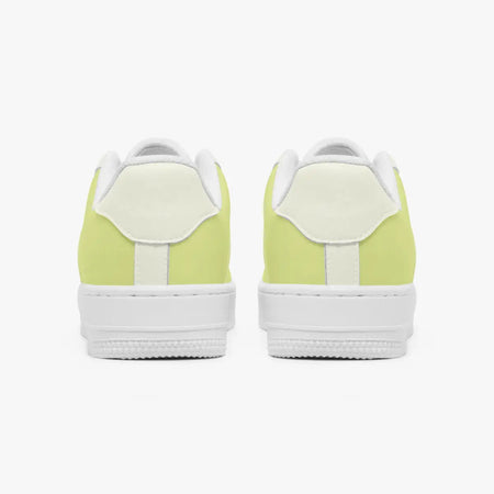 Rear view of a pair of pastel yellow and off-white sneakers showing the padded heel counters and flat white rubber soles.