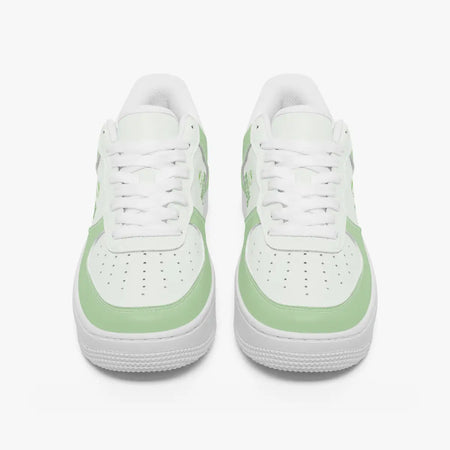 Front view of a pair of matcha green and white low-top leather sneakers with white laces and perforated toe caps.