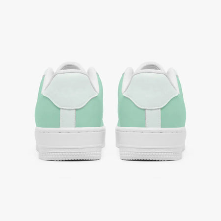 Rear view of mint green and white leather sneakers showing the padded heel counters and flat white rubber soles.
