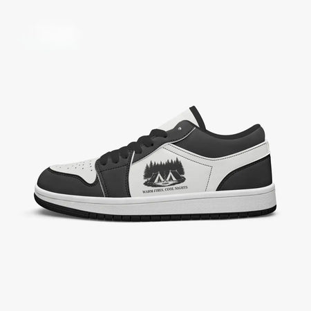 Side profile view of the right low-top sneaker in charcoal black and white leather, featuring a camping tents graphic with "WARM FIRES, COOL NIGHTS", black laces, and a black inner lining facing right.