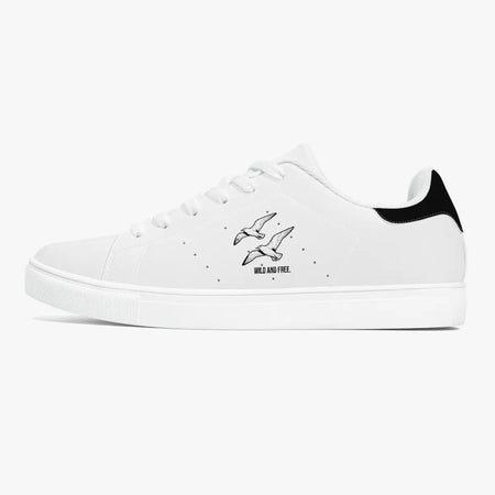 Side profile view of the left sneaker in white leather, showcasing the "WILD AND FREE" soaring birds illustration, black heel tab detail, white laces, and flat white rubber cupsole facing right.