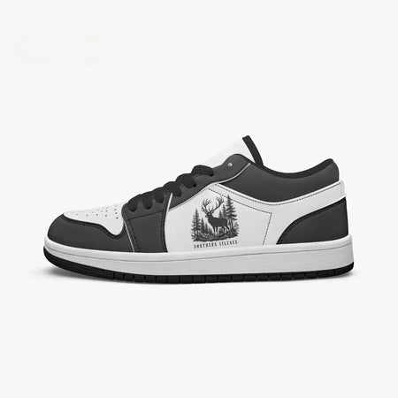 Side profile view of the right low-top sneaker in charcoal black and white leather, featuring a deer in a pine forest graphic with "NORTHERN SILENCE", black laces, and a black inner lining facing right.