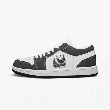 Side profile view of the right low-top sneaker in charcoal black and white leather, featuring a stag deer in a pine forest graphic with "NORTHERN SILENCE", white laces, and a flat rubber sole facing right.