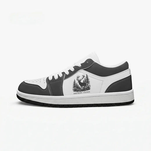 Side profile view of the right low-top sneaker in charcoal black and white leather, featuring a stag deer in a pine forest graphic with "NORTHERN SILENCE", white laces, and a flat rubber sole facing right.