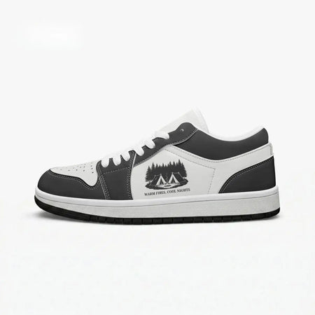 Side profile view of the right low-top sneaker in charcoal black and white leather, featuring a camp tents and pine forest graphic with "WARM FIRES, COOL NIGHTS", white laces, and a flat rubber sole facing right.