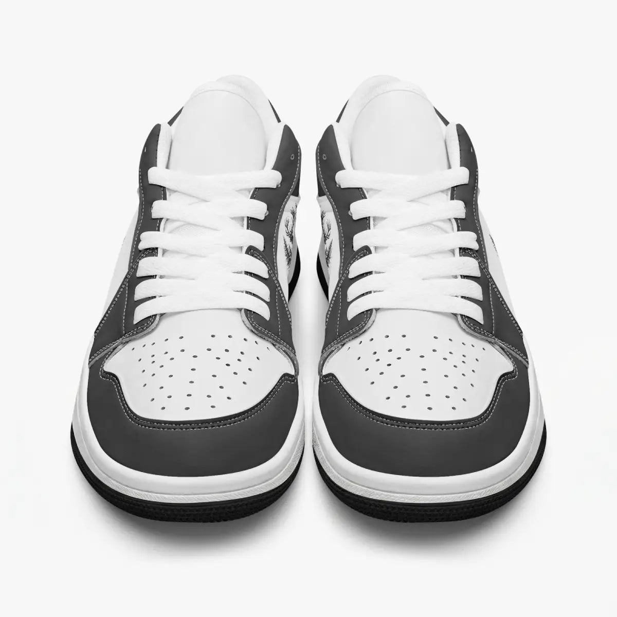 Front-facing top angle of black and white low-top sneakers displaying clean white laces, black eyestays, and perforated white toe boxes.