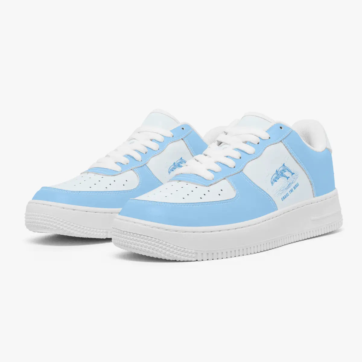 Angled three-quarter view of sky blue and white low-top sneakers, featuring a leaping dolphin graphic with "CHASE THE WAVE", white laces, and thick white rubber soles.