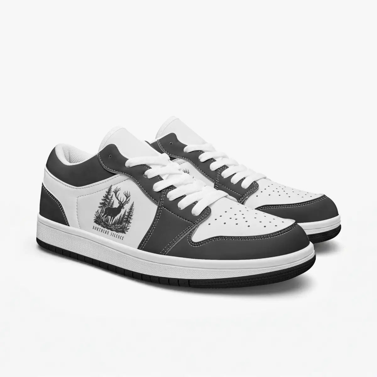 Angled three-quarter view of low-top sneakers in charcoal black and white leather, featuring a forest stag graphic with "NORTHERN SILENCE", white laces, and a white inner lining.