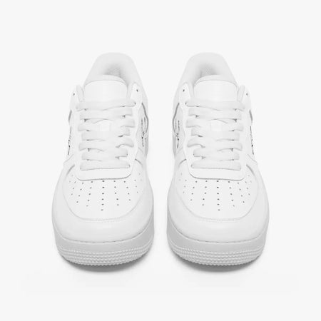 Front-facing top angle of monochromatic white leather low-top sneakers, displaying clean white laces, white eyestays, and perforated toe boxes.