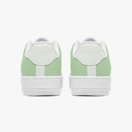 Rear view of a pair of sage green and white sneakers showing the padded heel counters and flat white rubber soles.