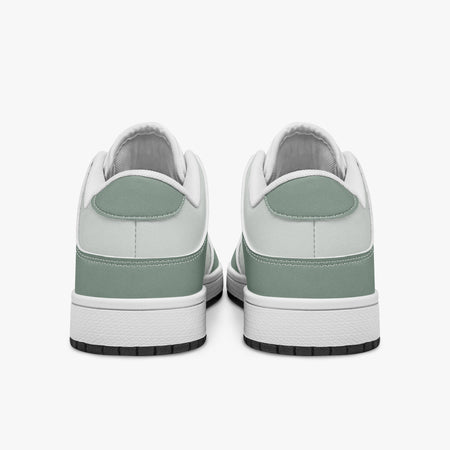 Rear view of sage green and off-white sneakers displaying sage green heel overlays, off-white collar panels, and two-tone white and black rubber outsoles.