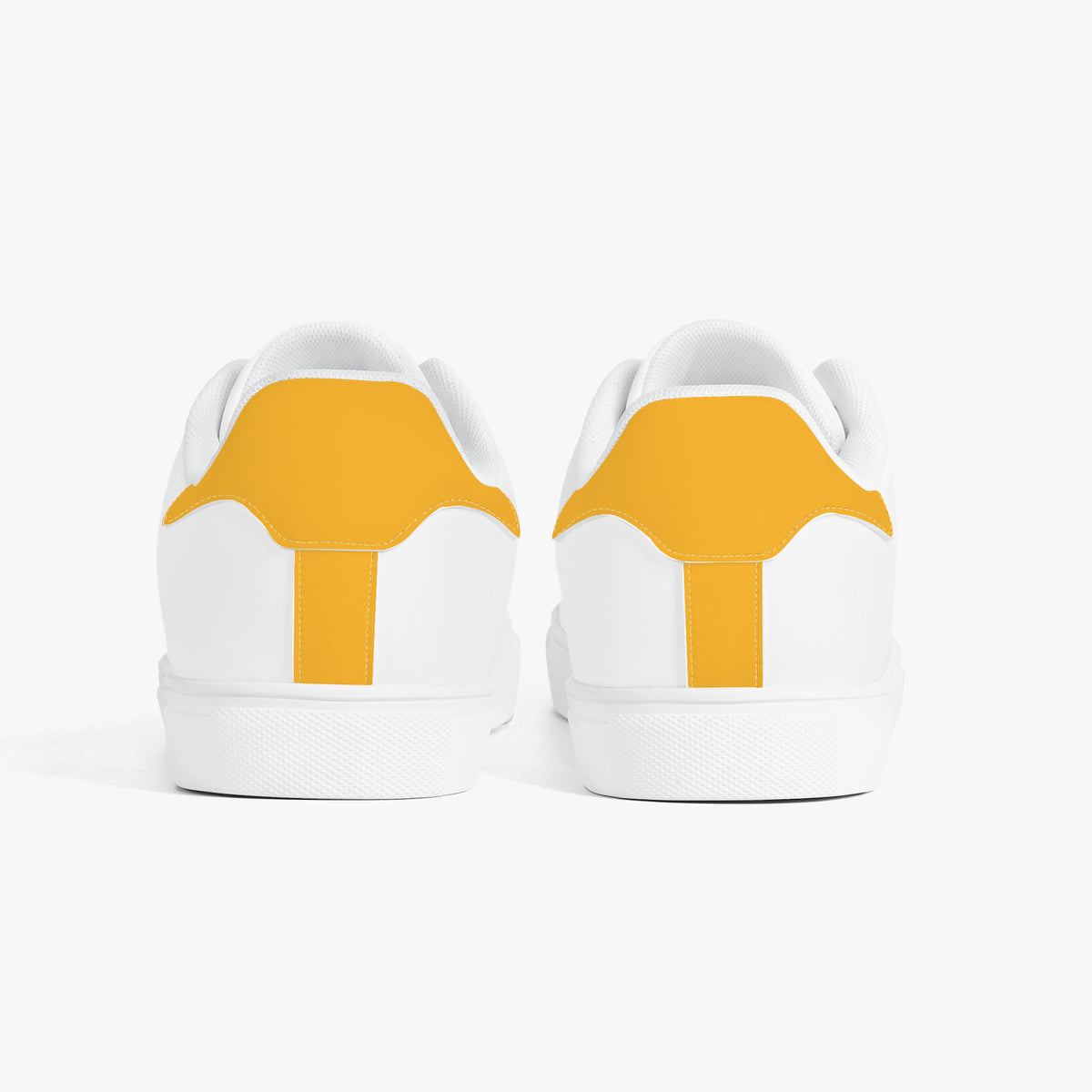 A pair of white low-top sneakers shown from the back, featuring a bold mustard yellow accent panel on the heel area, set against a clean white background.