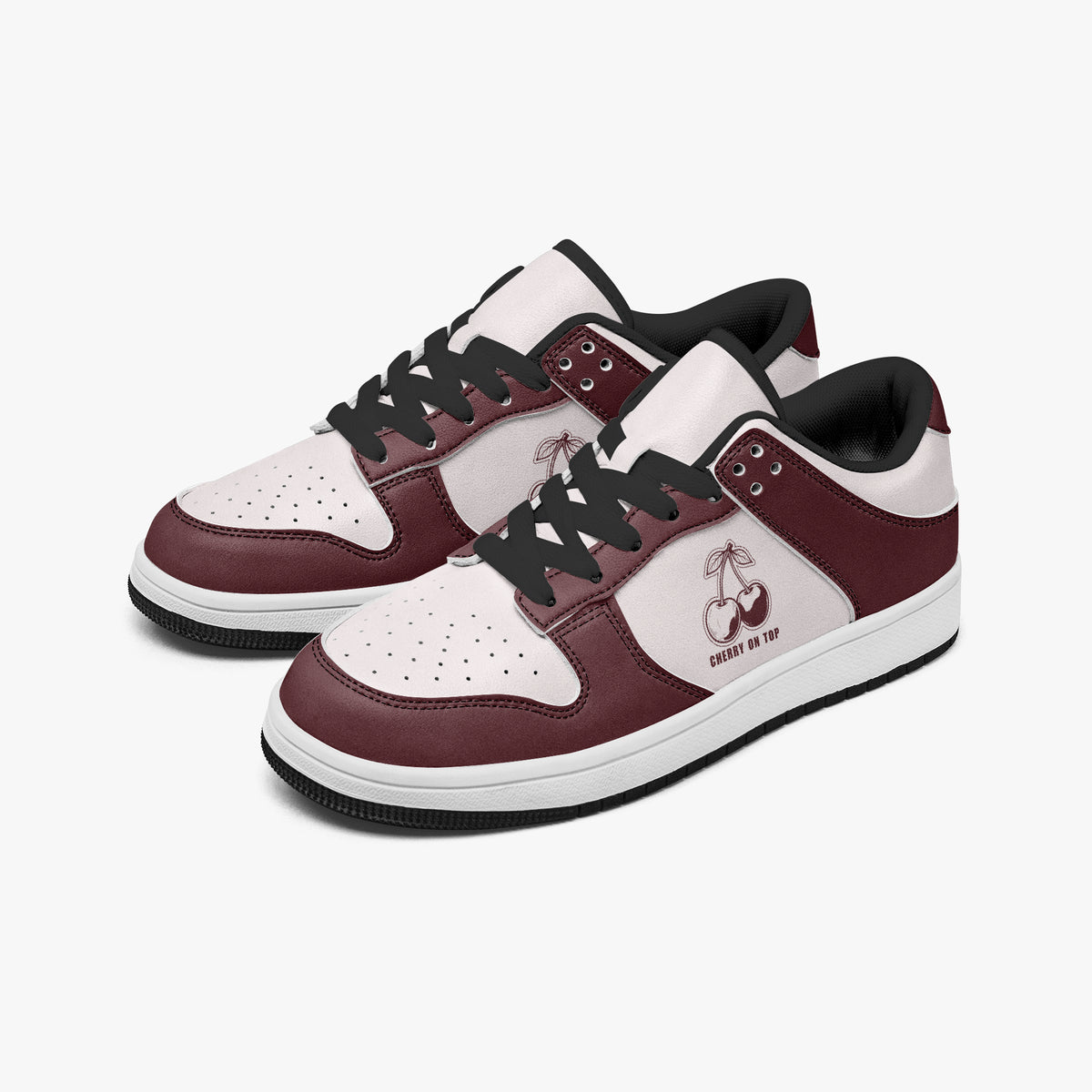 Angled three-quarter view of low-top sneakers in burgundy and pale pink leather, featuring a cherry graphic with "CHERRY ON TOP", black laces, and a black inner lining.