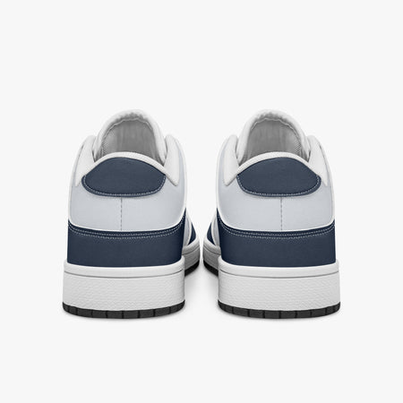 Rear view of the sneakers displaying navy blue heel overlays, white leather collar lining, and two-tone white and black rubber outsoles.