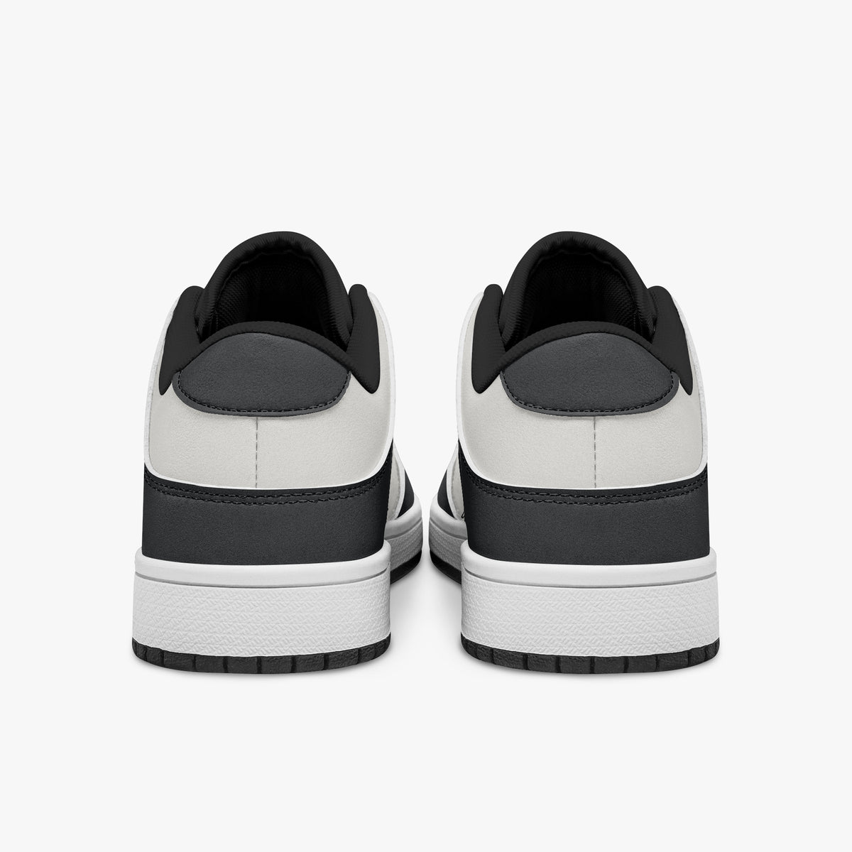 Rear view of black and white sneakers showing dark charcoal heel overlays, white leather collars, and black interior collar lining above white midsoles.