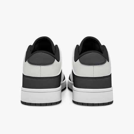 Rear view of black and white sneakers showing dark charcoal heel overlays, white leather collars, and black interior collar lining above white midsoles.