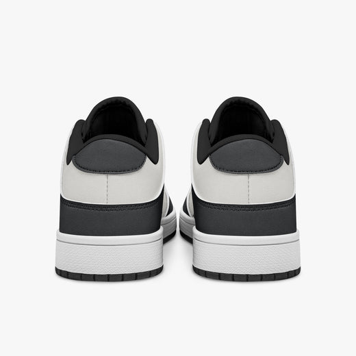 Rear view of black and white sneakers showing dark charcoal heel overlays, white leather collars, and black interior collar lining above white midsoles.