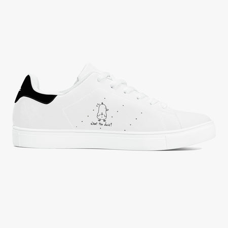 A white low-top sneaker with a black heel tab, white laces, and a small black cartoon graphic with the text 'what do we?' on the side, shown against a plain white background.