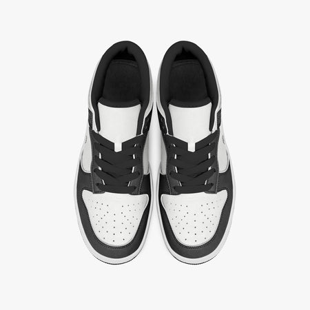 Overhead view of black and white sneakers displaying black laces, black padded collar lining, and perforated white leather toe boxes.