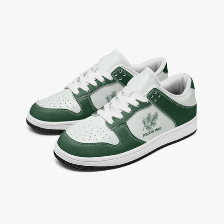 Angled three-quarter view of low-top sneakers in forest green and white leather, featuring a botanical branch illustration with "PEACE OF MIND", white laces, and a white inner lining.