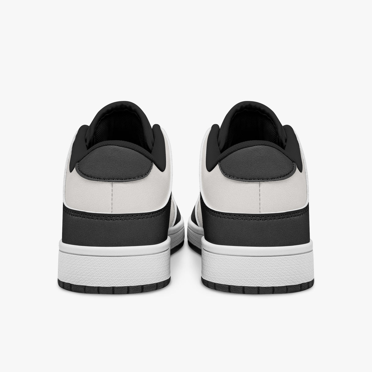 Rear view of black and white sneakers showing dark charcoal heel overlays, white leather collars, and black interior collar lining above white midsoles.