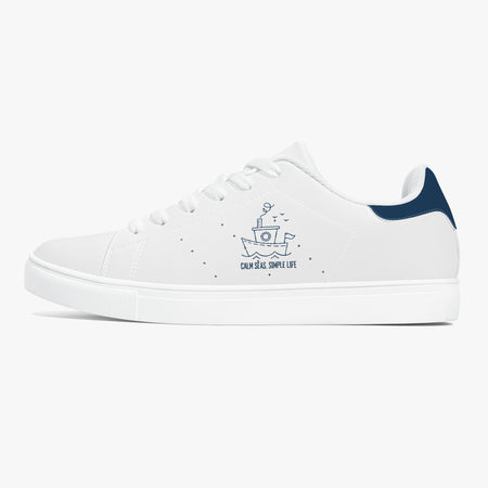 A white low-top sneaker with a navy blue heel tab, featuring a navy blue boat graphic and the text 'CANYON BIG SHIP LIFE' on the side, set against a light gray background.