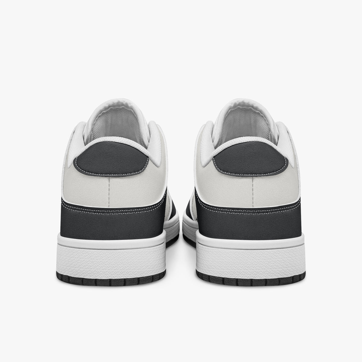 Rear view of black and white sneakers displaying dark charcoal heel overlays, white leather collar panels, and two-tone white and black rubber outsoles.