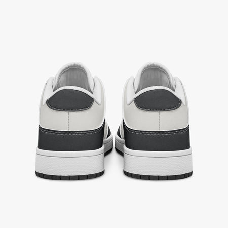 Rear view of black and white sneakers displaying dark charcoal heel overlays, white leather collar panels, and two-tone white and black rubber outsoles.